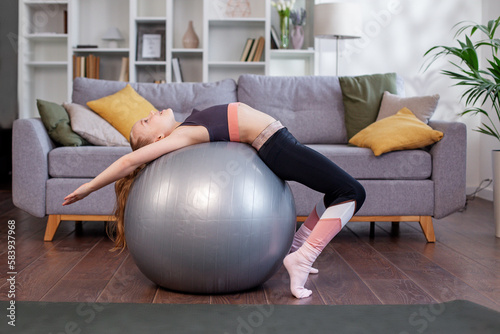 Child girl doing exercises with swiss ball indoor. Sports concept.