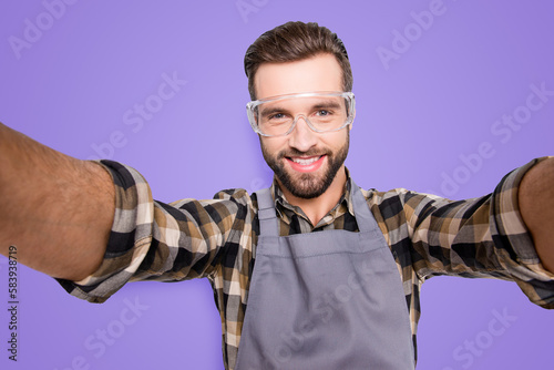 Self portrait of cheerful attractive man with stubble shooting selfie with two hands on front camera of smart phone during break, pause, time out, having res relax, isolated over grey background photo