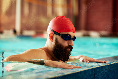 Swimmer athlete man resting at the side of the pool taking a break during training swims, swimming in the pool, training in the water