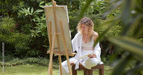 Creative young female artist painting a picture with acrylic paints outdoors. Creativity, hobby and art concept