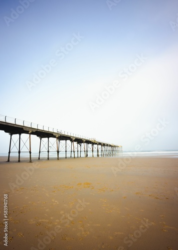 Vertical shot of the pier at the seaside town of Saltburn-by-the-Sea on a misty day, North Yorkshire © Pez Photography/Wirestock Creators