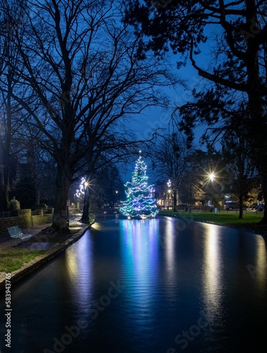 Colorful decorated Christmas tree in the river at Bourton-on-the-Water in The Cotswolds