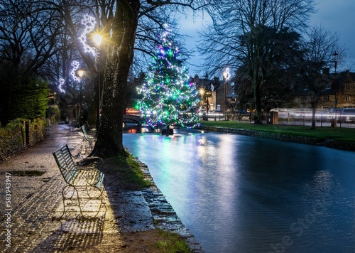 Colorful decorated Christmas tree in the river at Bourton on the Water in the Cotswolds