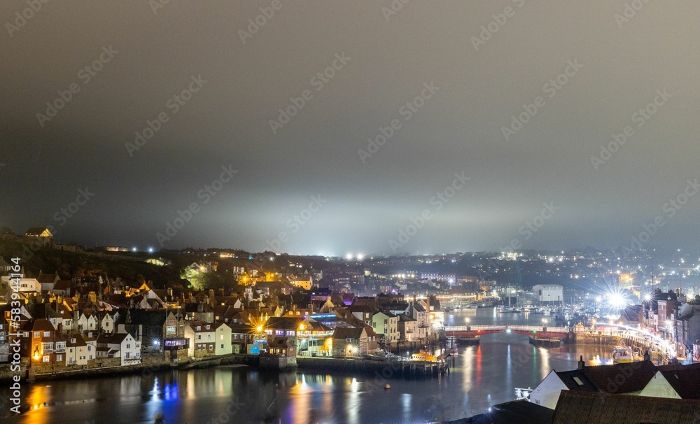 Aerial view of illuminated Whitby harbor on a foggy evening in Yorkshire, England