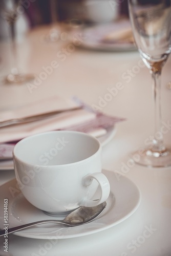 Selective focus shot of an empty white tea cup with spoon on a table laid for English afternoon tea
