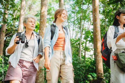 woman family walking in the forest to watching a bird in nature, using binocular for birding by looking on a tree, adventure travel activity in outdoor trekking lifestyle, searching wildlife in jungle © chokniti