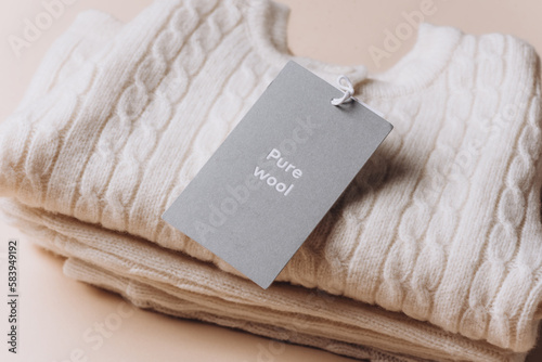 Label with Text Wool on merino wool clothes. Tag composition of clothing on knitted texture background. Set of wool organic baby clothes photo