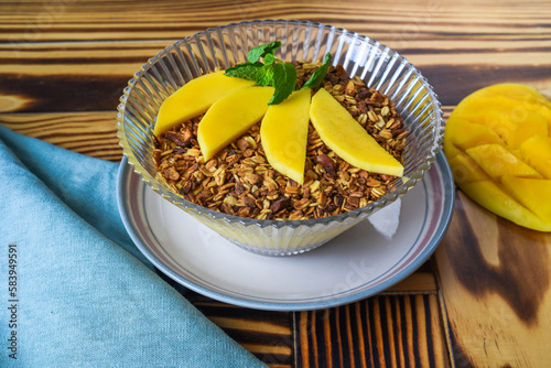 Granola served with mango on a wooden table close up