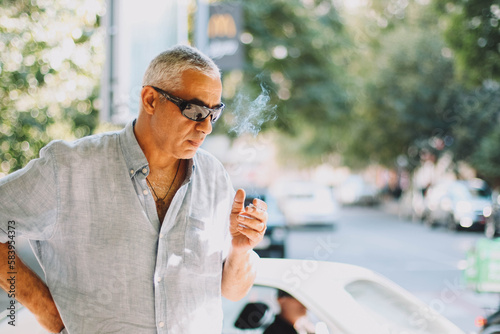 An old senior man smoking cigarette outside. smoke addiction, bad habbit. 