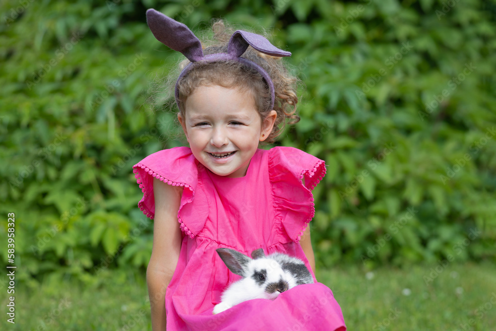 little cute girl with hear ears playing with little rabbit. Child with pet bunny outdoors. Happy kid with animal. Happy Easter concept little cute girl with hear ears playing with little rabbit. Child with pet bunny outdoors. Happy kid with animal. Happy Easter concept