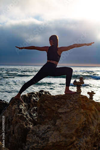 a young female doing yoga exercises on the stone near the ocean. yoga asanas