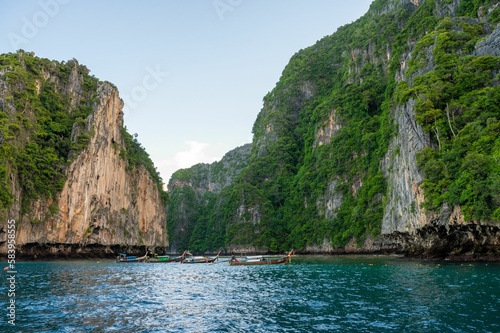 Boats on the blue water of the ocean surrounded by cliffs
