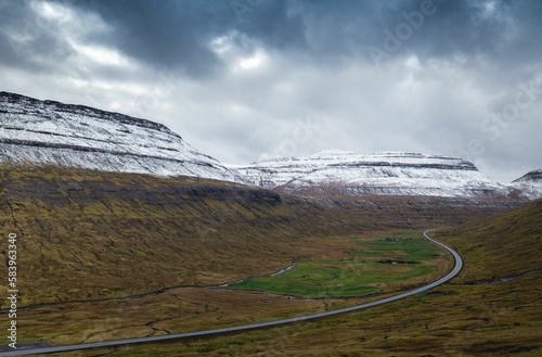 Landscape view of the narrow road between the snow-covered rocks on a clouded day