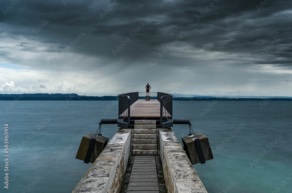 Scenic shot of a dock in the middle of a vast sea under a cloudy gloomy sky