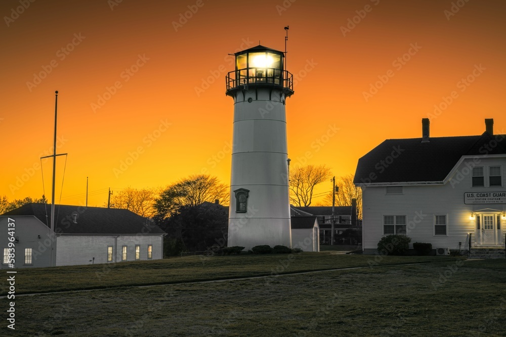 Beautiful shot of a lighthouse among rural buildings in Chatham, Cape Cod, Massachusetts at sunset