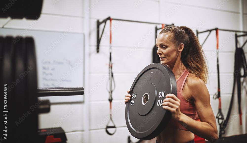 Fit mature woman preparing for a workout with heavy weights Fit mature woman preparing for a workout with heavy weights