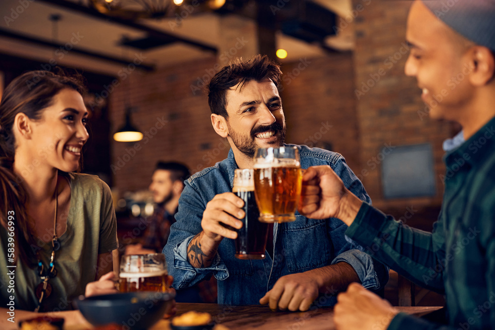 Young happy man and his friend toasting with beer in bar.