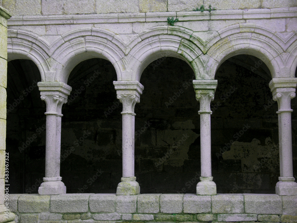 The arches of the monastery of Santo Estevo in Galicia are made of stone and covered with green moss.