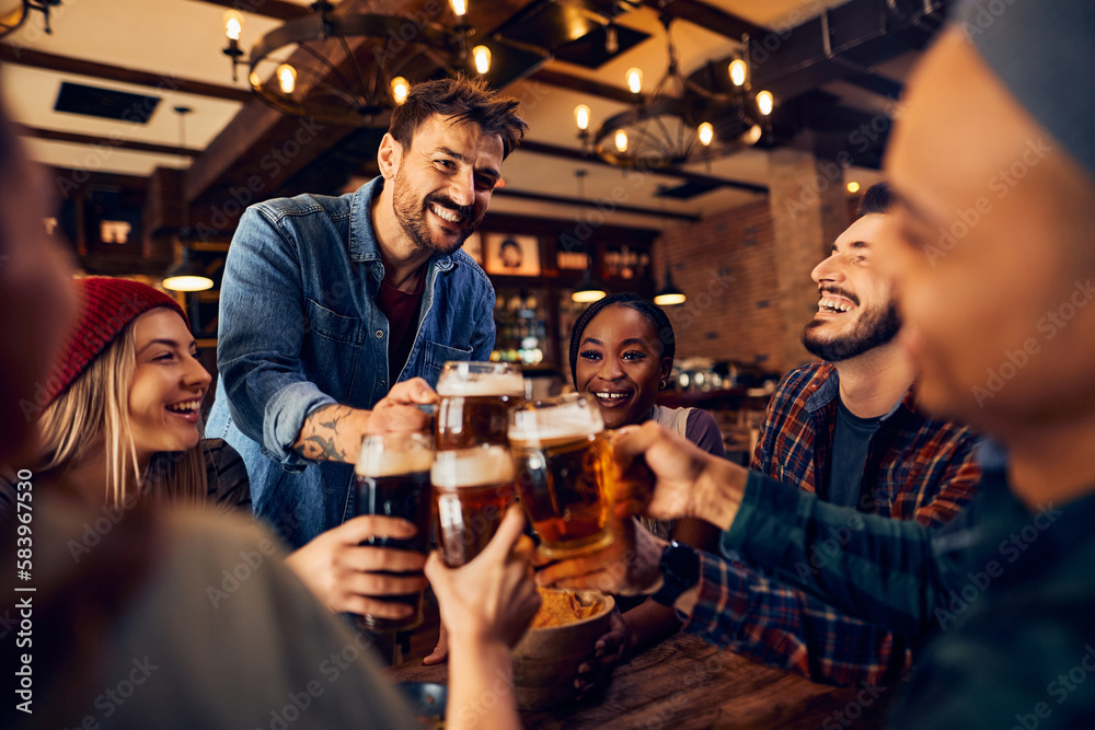 Happy man and his friends toast with beer while gathering in pub.
