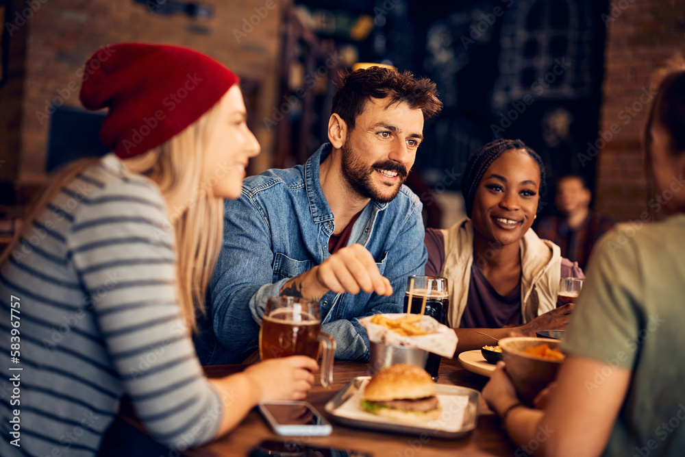 Happy man enjoys while communicating with his friends in pub.