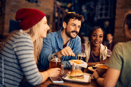 Happy man enjoys while communicating with his friends in pub.