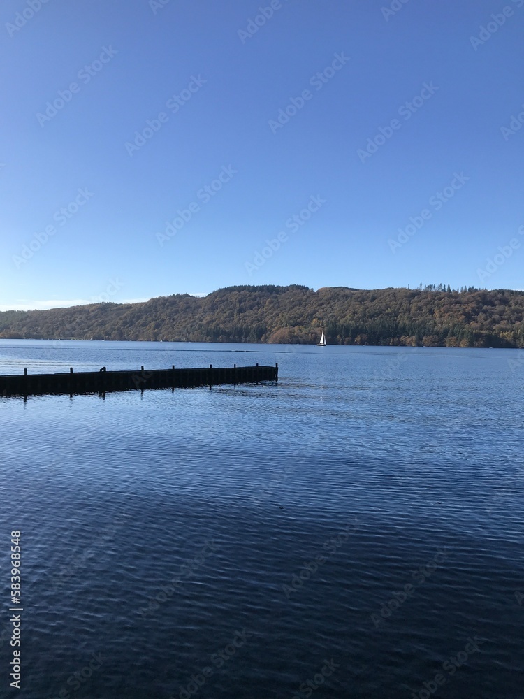 Lake view with a wooden jetty and a blue sky background. Lake Windermere England. 
