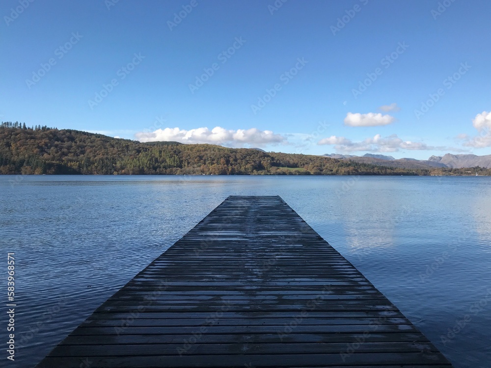 Lake view with a wooden jetty and a blue sky background. Lake Windermere England. Lake view with a wooden jetty and a blue sky background. Lake Windermere England.