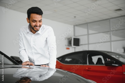 happy indian man checking car features at showroom © Serhii