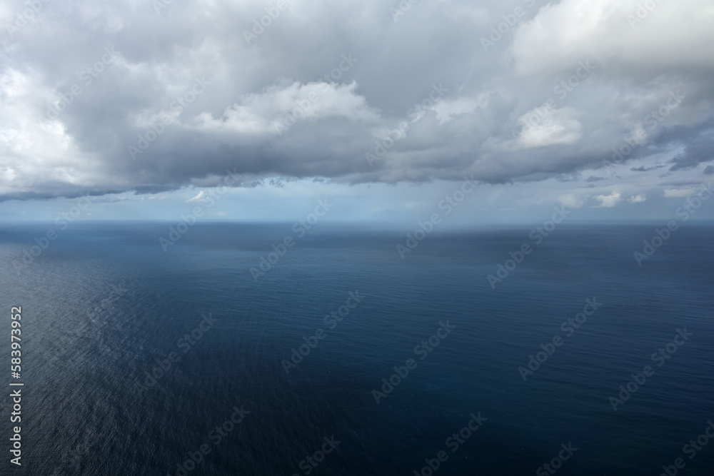Das weite blaue Meer und aus der Bewölkung fällt leichter regen am Horizont