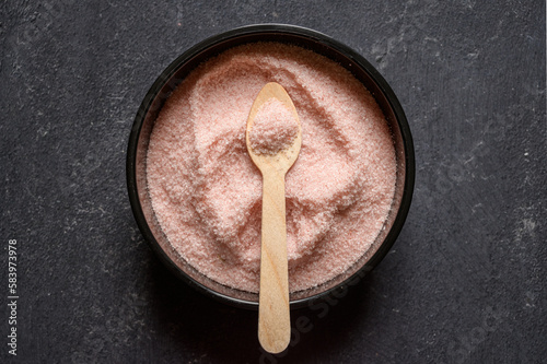 Himalayan pink salt in a black bowl with wooden spoon