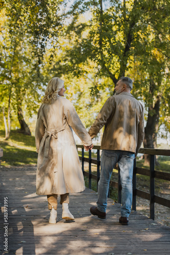 Side view of carefree mature couple having conversation and walking in park.