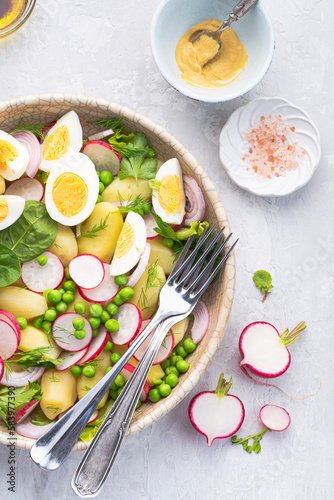 Spring salad with baby potatoes, radishes, farmer organic  eggs and green peas and herbs, seasoned with olive oil, mustard sauce, balsamic and lemon.  Spring vegetarian diet, clean healthy lunch
