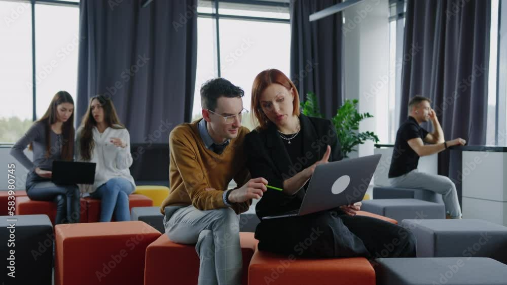 Colleagues with a laptop work sitting in open space. Brainstorming , a small startup Colleagues with a laptop work sitting in open space. Brainstorming , a small startup