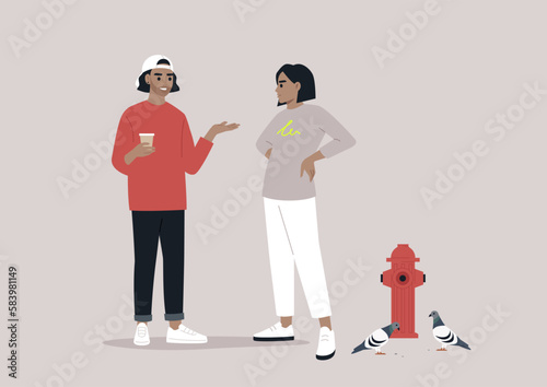 In an urban atmosphere, two young hipsters encountered each other on the street, engaging in conversation while one sipped on a to-go coffee near a fire hydrant and a flock of pigeons