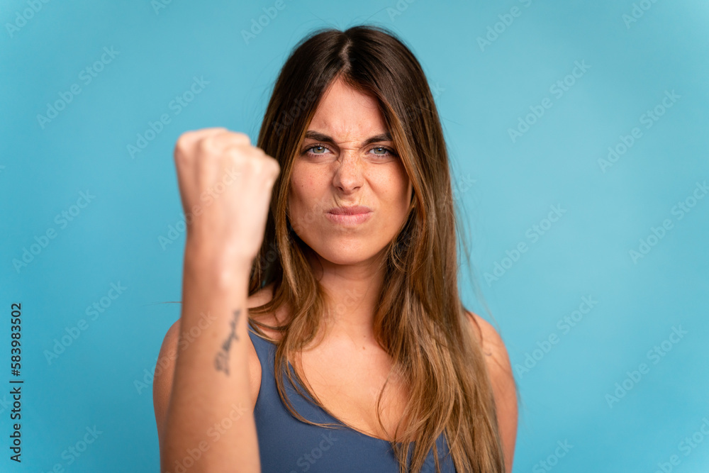 Young woman with long hair in studio showing fist Young woman with long hair in studio showing fist