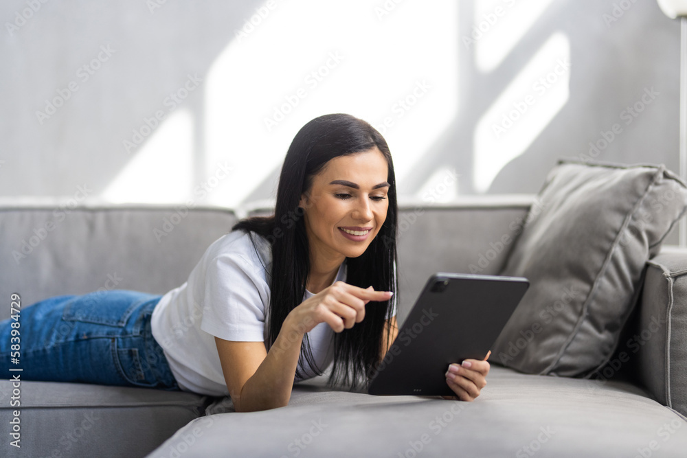 Young woman using digital tablet on couch at home Young woman using digital tablet on couch at home