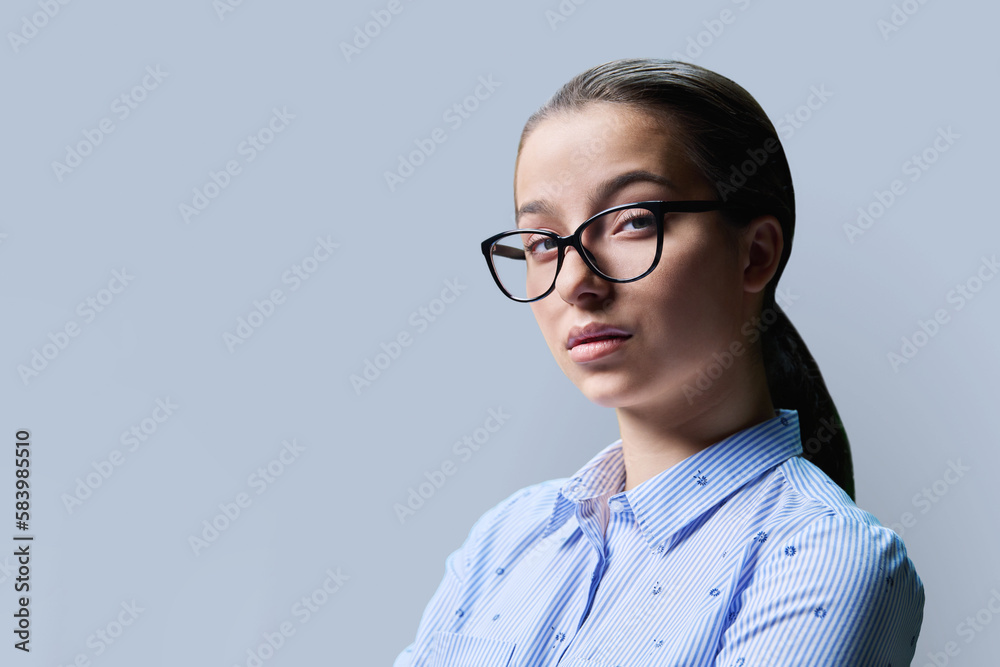 Portrait of a high school student girl, copyspace gray background. Close up confident serious female in glasses looking at camera Portrait of a high school student girl, copyspace gray background. Close up confident serious female in glasses looking at camera
