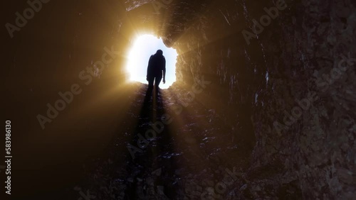 Woman walks in a stone tunnel with rays