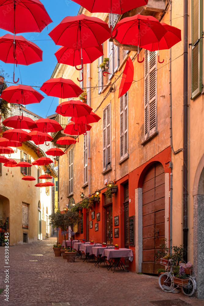 Fototapeta premium vertical view of a cobblestone street with small shops and colorful decorations in the old city center of Luino