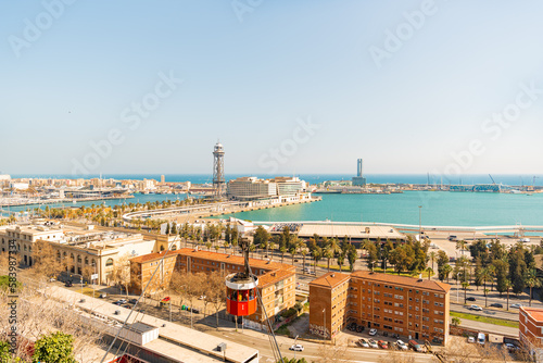 View of Barcelona from the hill. Sea and horizon. People ride in a red cabin on a cable car into the distance. Tourism in Spain. Transport type.