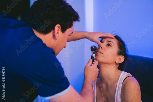 Practicing physician checking the nostrils of a Latin woman.
