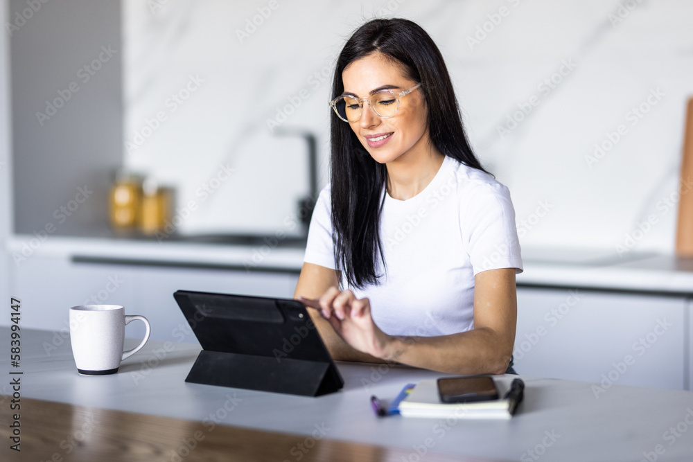 Young pretty woman using a tablet computer to cook in her kitchen . Young pretty woman using a tablet computer to cook in her kitchen .