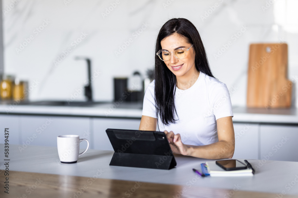 Young pretty woman using a tablet computer to cook in her kitchen . Young pretty woman using a tablet computer to cook in her kitchen .