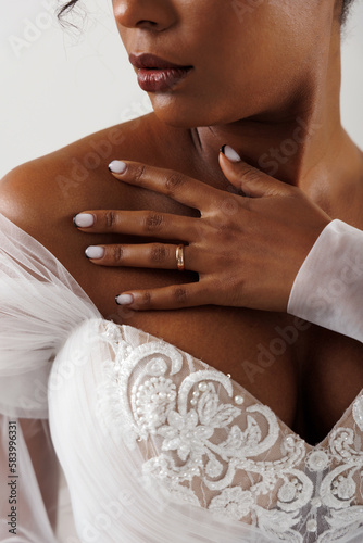 African American model posing in a wedding dress. Hands and wedding ring close-up.