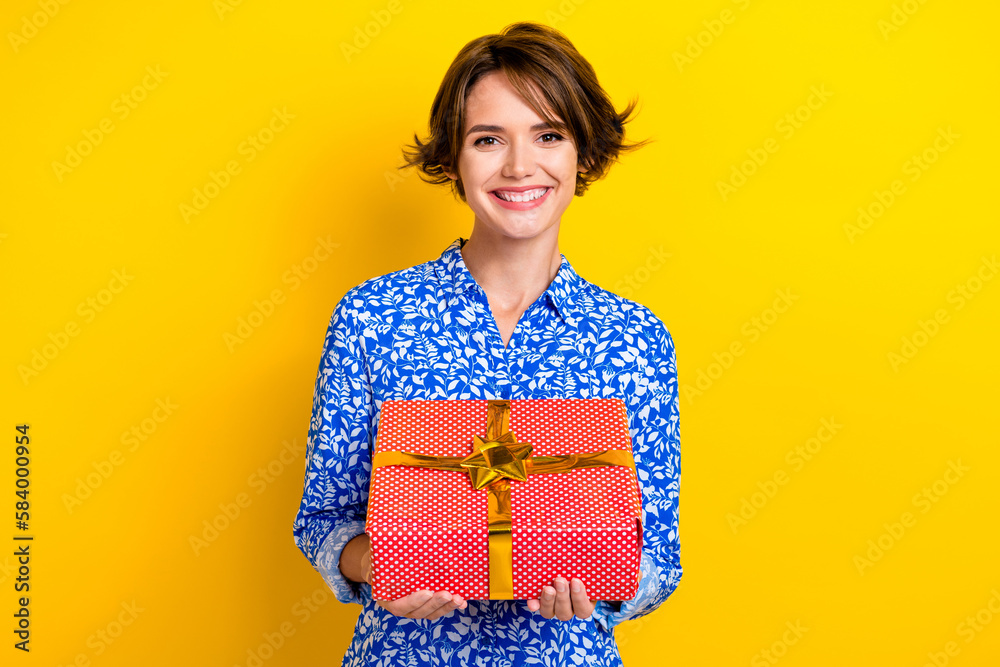 Photo of sweet adorable woman dressed blue blouse holding red present box isolated yellow color background Photo of sweet adorable woman dressed blue blouse holding red present box isolated yellow color background