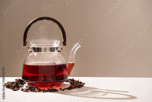 Red hibiscus tea from the petals of a Sudanese rose in a glass teapot, copy the place for the text