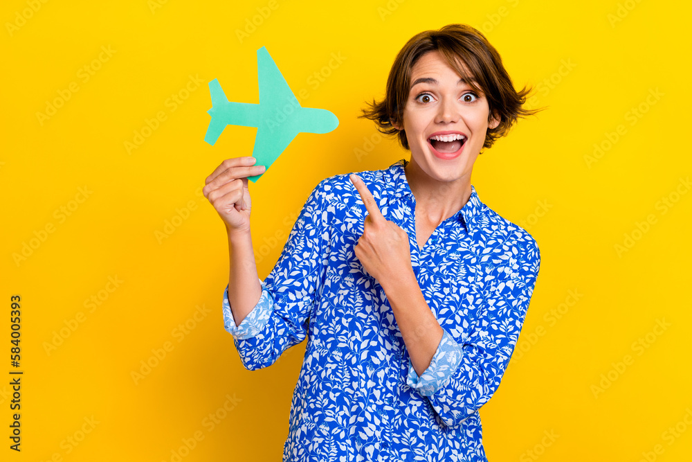 Photo portrait of pretty young girl hold point paper plane business trip wear trendy print clothes isolated on yellow color background Photo portrait of pretty young girl hold point paper plane business trip wear trendy print clothes isolated on yellow color background