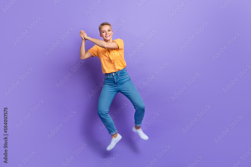 Full length photo of friendly playful girl dressed jeans white sneakers hold imaginary tennis racket isolated on violet color background