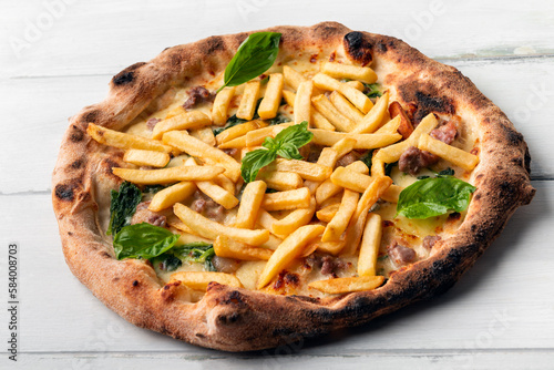 Deliziosa pizza italiana condita con salsiccia di maiale, spinaci e patatine fritte  photo