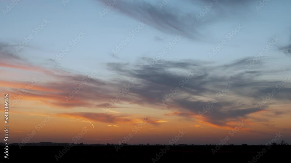Time Lapse Colorful Sunset in a Field of Orange Blue Red Lilac Sky Sun and Light Cirrus Clouds. Beautiful Sunset Sky in the Meadow. Amazing 4K Natural Landscape Background. Time Lapse Colorful Sunset in a Field of Orange Blue Red Lilac Sky Sun and Light Cirrus Clouds. Beautiful Sunset Sky in the Meadow. Amazing 4K Natural Landscape Background.